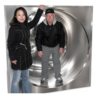 Two people standing inside a large round PRIMO tank, showing the open corner-free interior